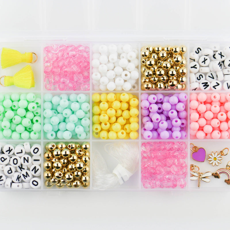 A storage box filled with pastel colorful beads, charms, and tassels.