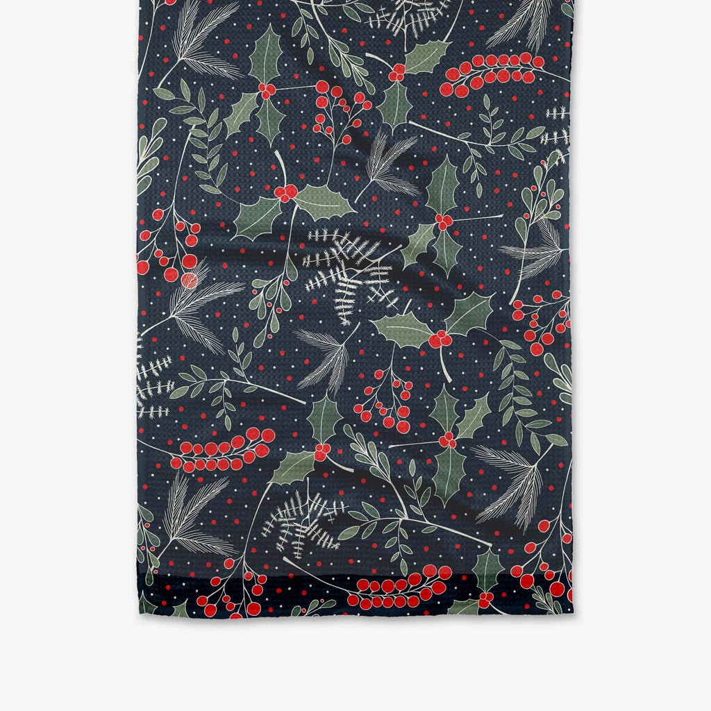 A navy blue tea towel printed with mistletoe and holly florals.