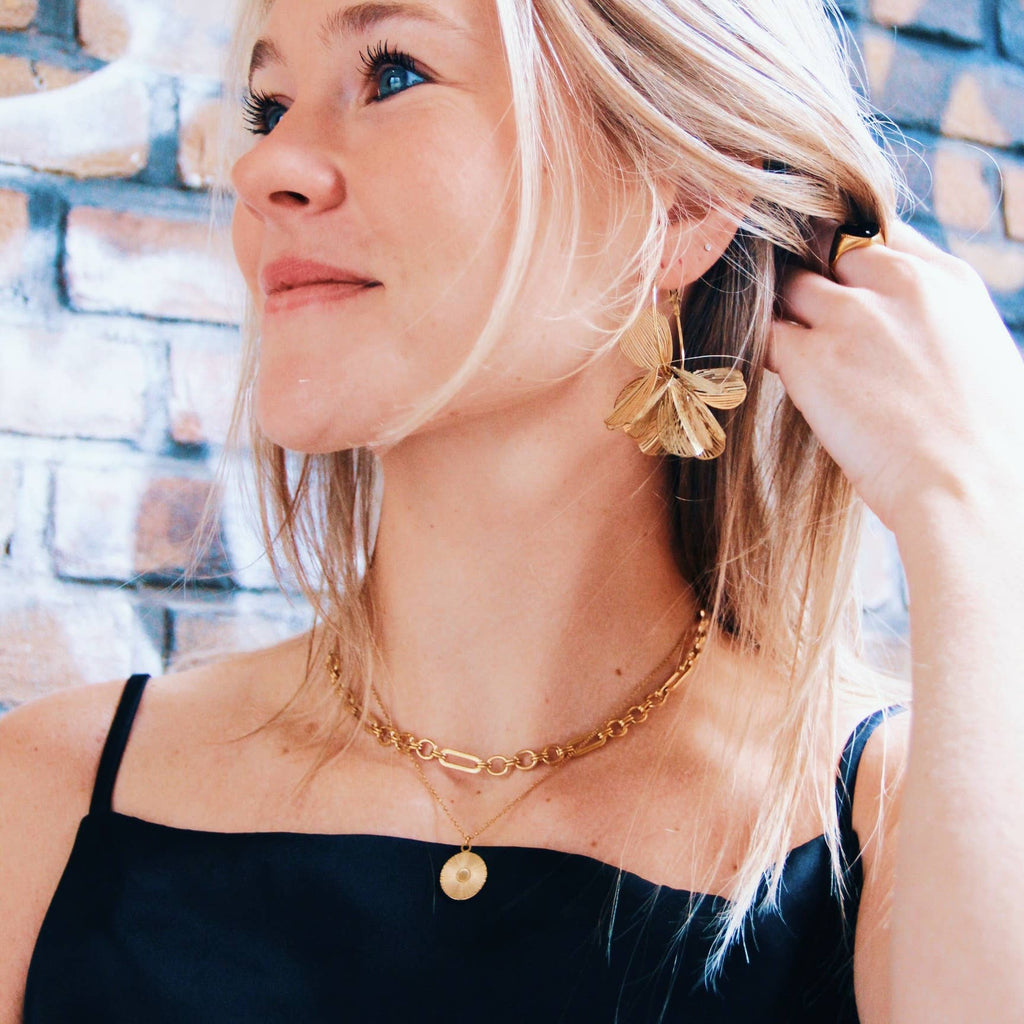 A person wearing the Round Clasp Chain Choker in Gold stacked with a pendant necklace.