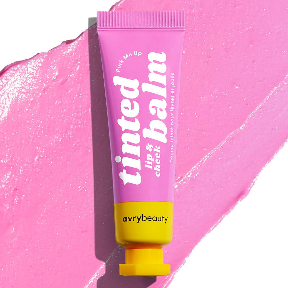 A pink tube with a yellow cap  filled with tinted balm with petal pink balm spread behind it.