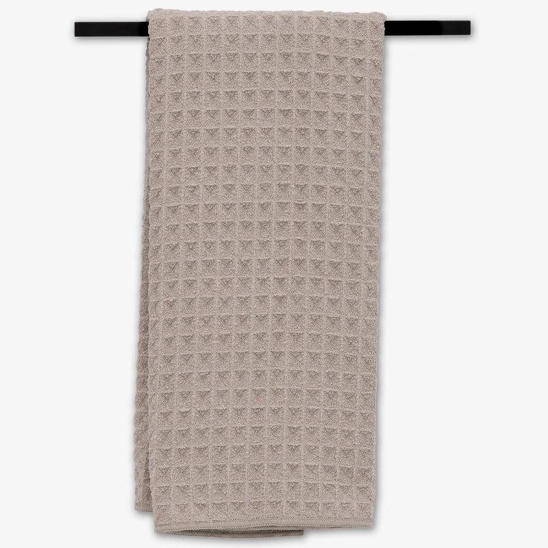 The Taupe Waffle Hand Towel hanging from a towel rack.