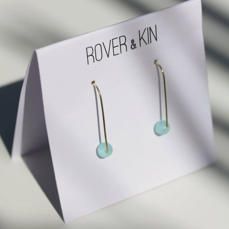 The Sea Glass Threader Earrings in Aqua on its folded paper packaging