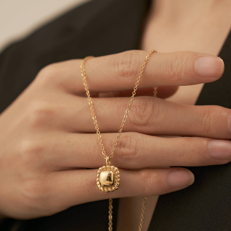 A hand holding the Square Pendant Necklace.