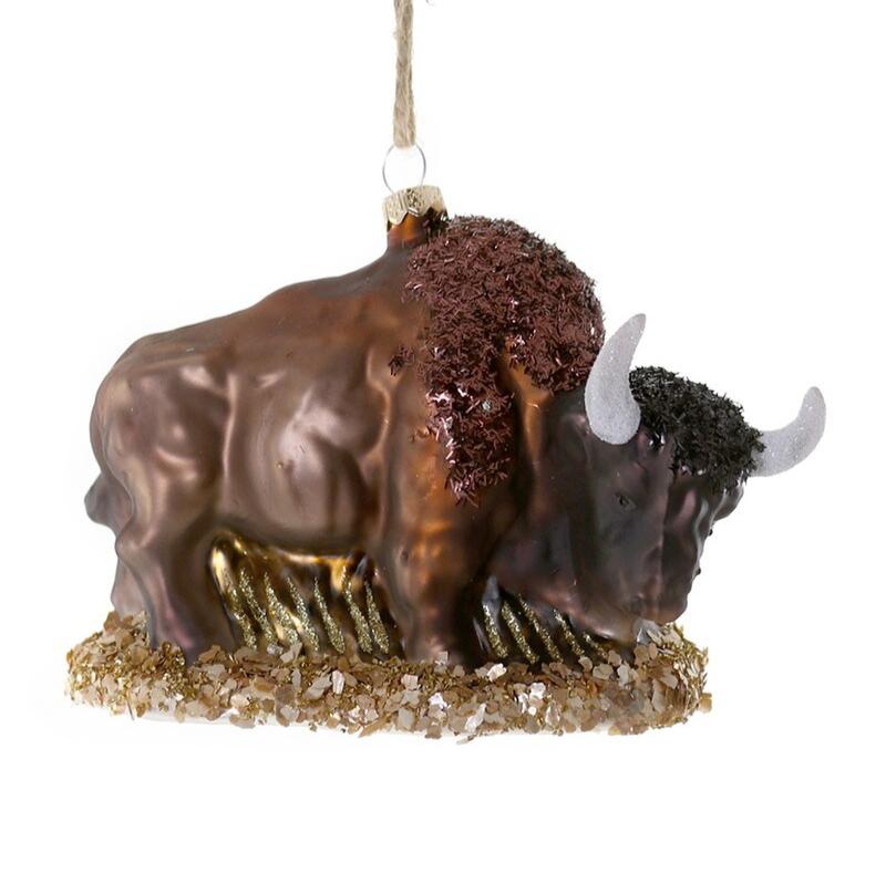 A glass bison ornament with glitter on the head and shoulders to mimic its fur and a brown cord to hang from the tree.