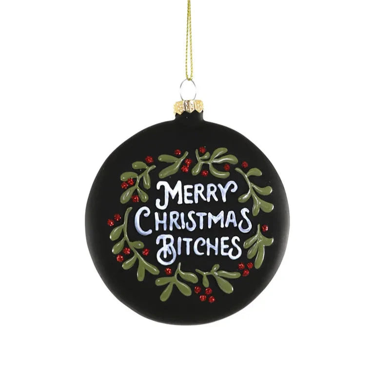 A circular matte black ornament with the words "Merry Christmas B*tches" uncensored surrounded by glittery holly and branches.