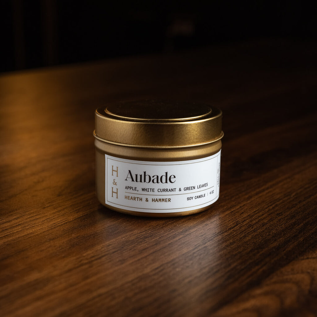 A closed Aubade candle resting on a deep wooden table