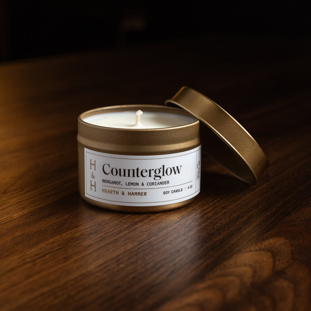 An open Counterglow candle in an antique gold travel tin with its lid leaning against it.