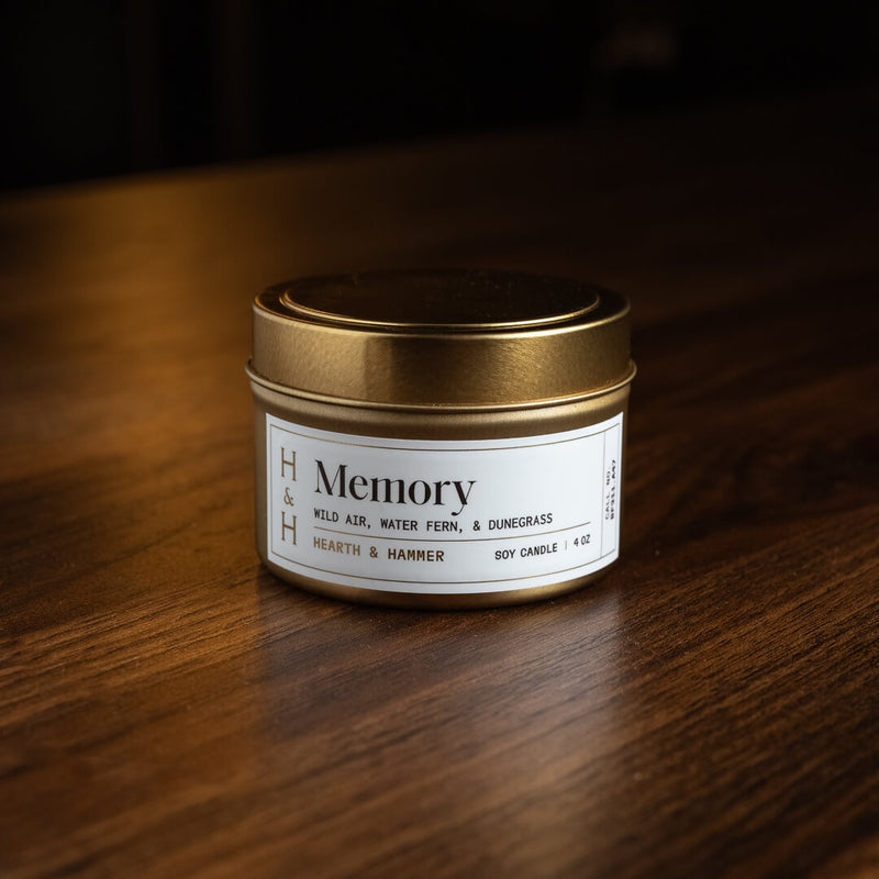 A Memory candle tin with its lid on resting upon a dark wooden table.