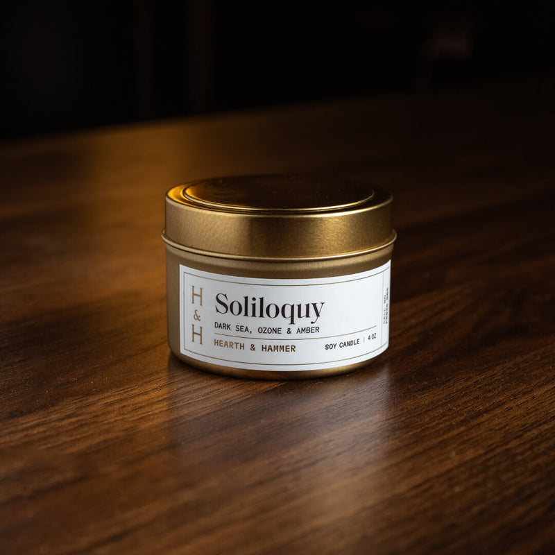 A closed Soliloquy candle on a  dark wooden table.