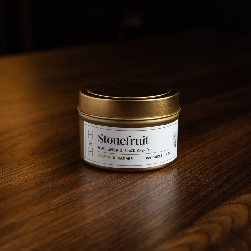 A closed Stonefruit candle tin resting on a dark wooden table.