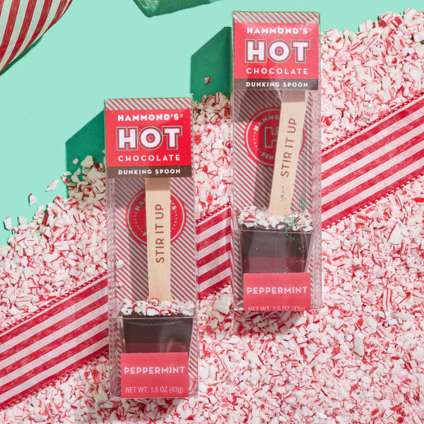 Two hot chocolate dunking spoons on a bed of crushed candy canes.