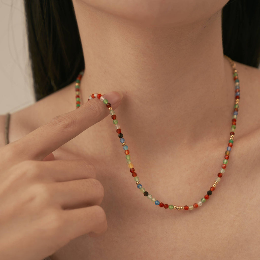 A person wearing a fine necklace strung with colorful beads.