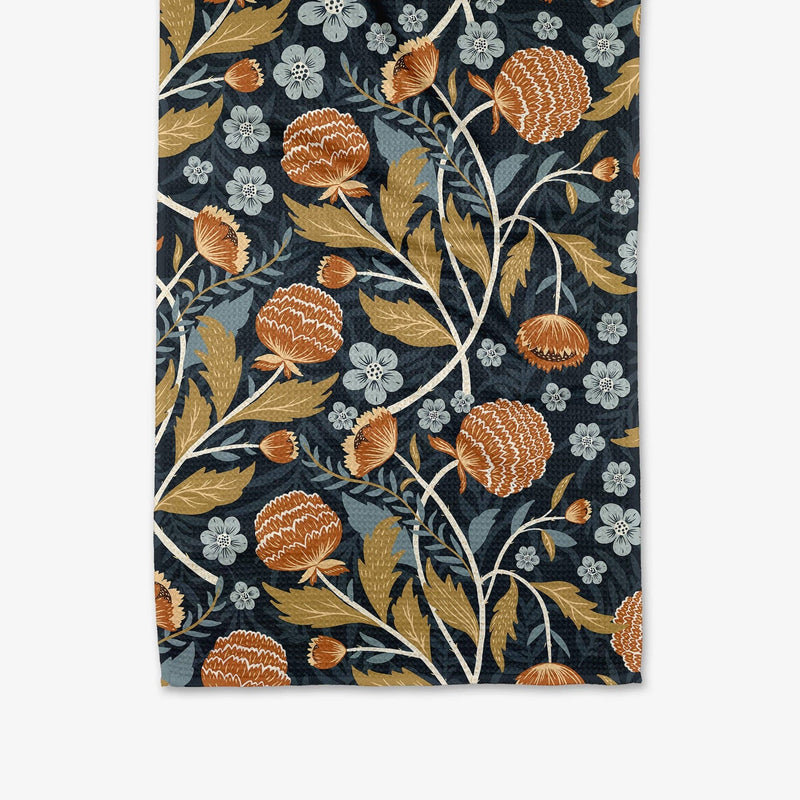 A navy blue tea towel patterned with orange and blue flowers and green botanicals.