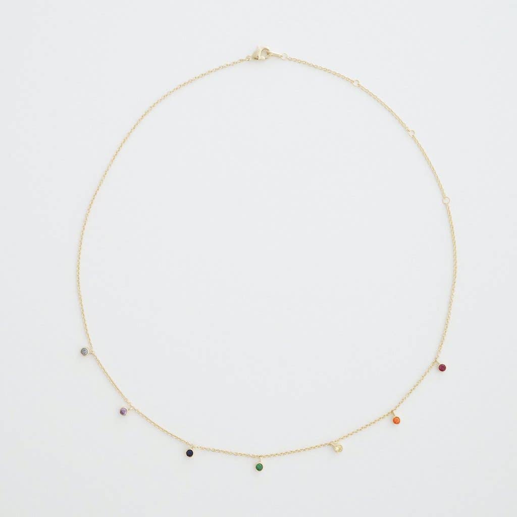 A fine gold chain necklace with rainbow crystals hanging evenly dispersed between one another.