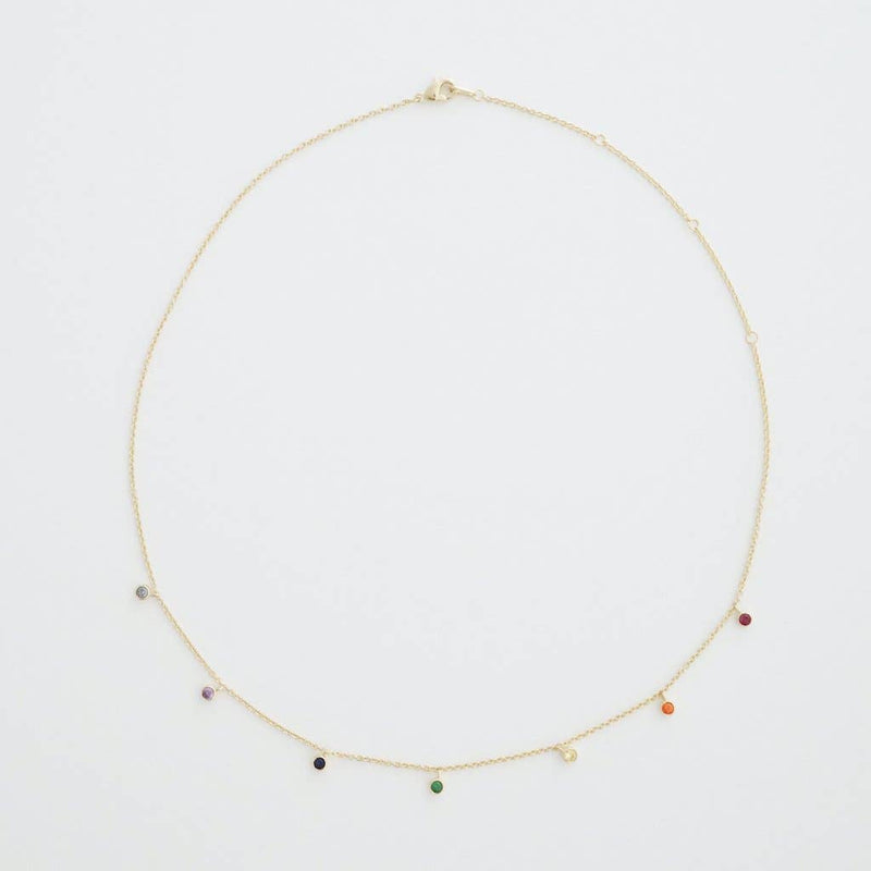 A fine gold chain necklace with rainbow crystals hanging evenly dispersed between one another.