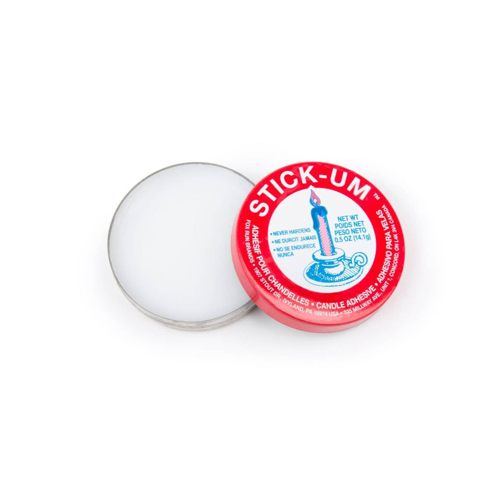 An open tin of white Candle Adhesive with a red lid.