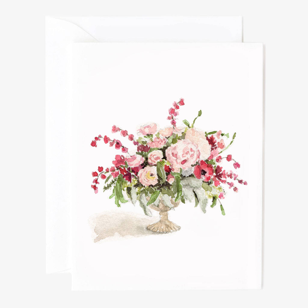 A white notecard watercolor illustrated with pink flowers in a cream vase with a white envelope behind.