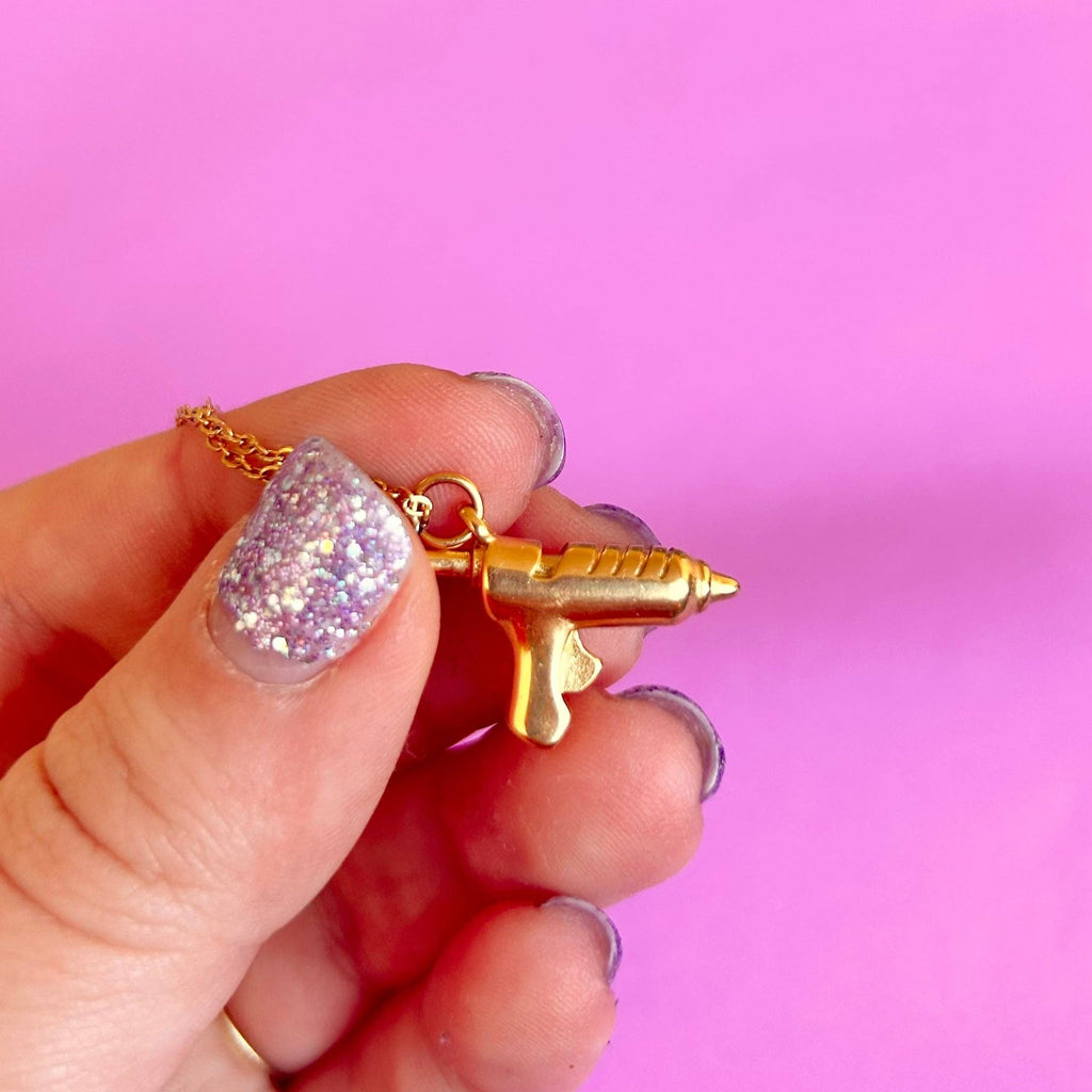 A hand holding the hot glue gun charm.