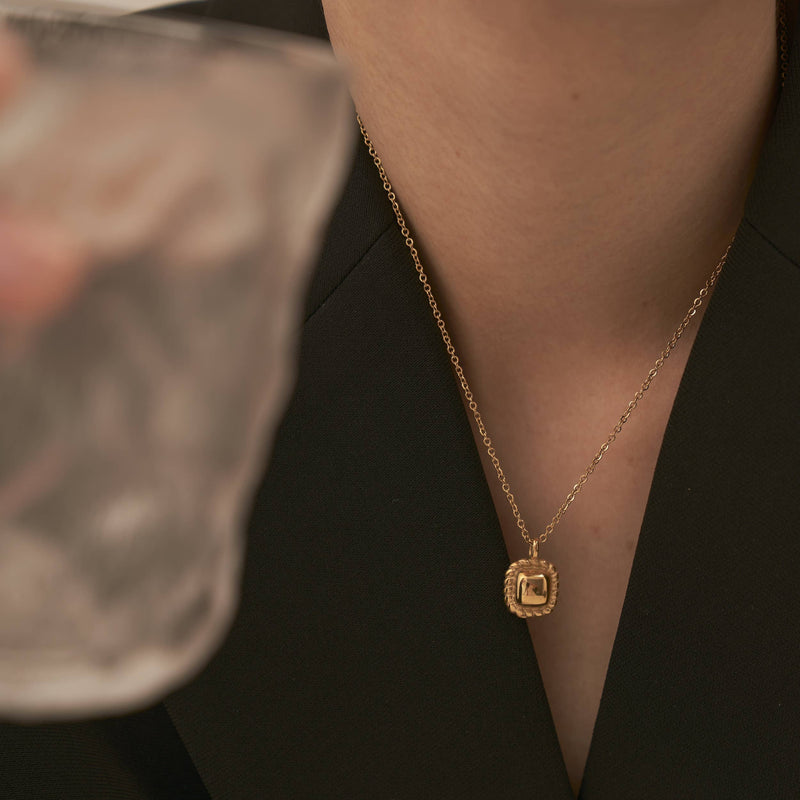 The Square Pendant Necklace dangling from someone's neck.