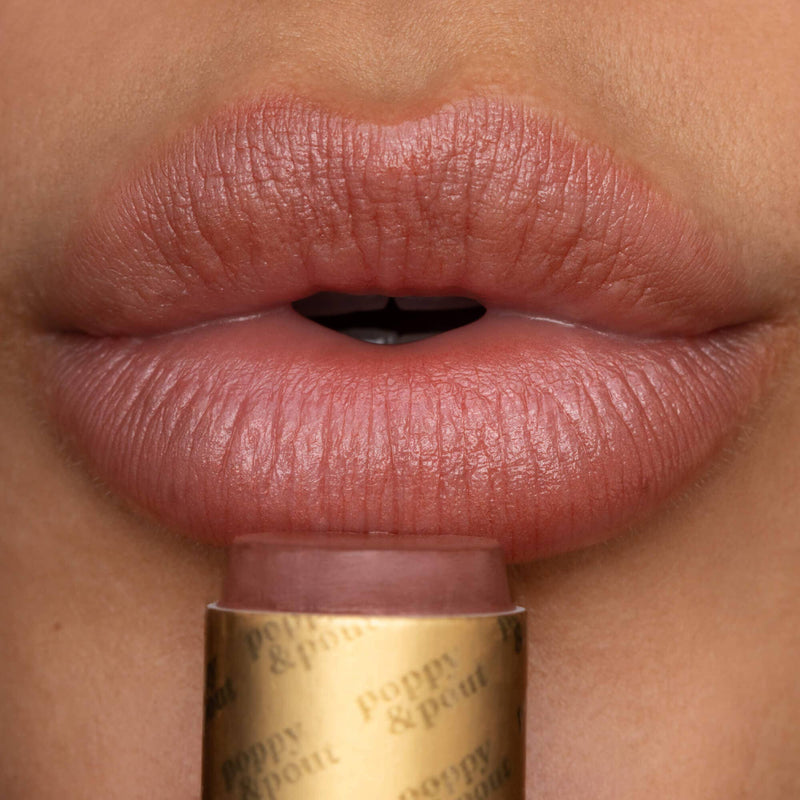 A close-up of a person wearing the Debbie Lip Tint with the tube just below their lips.