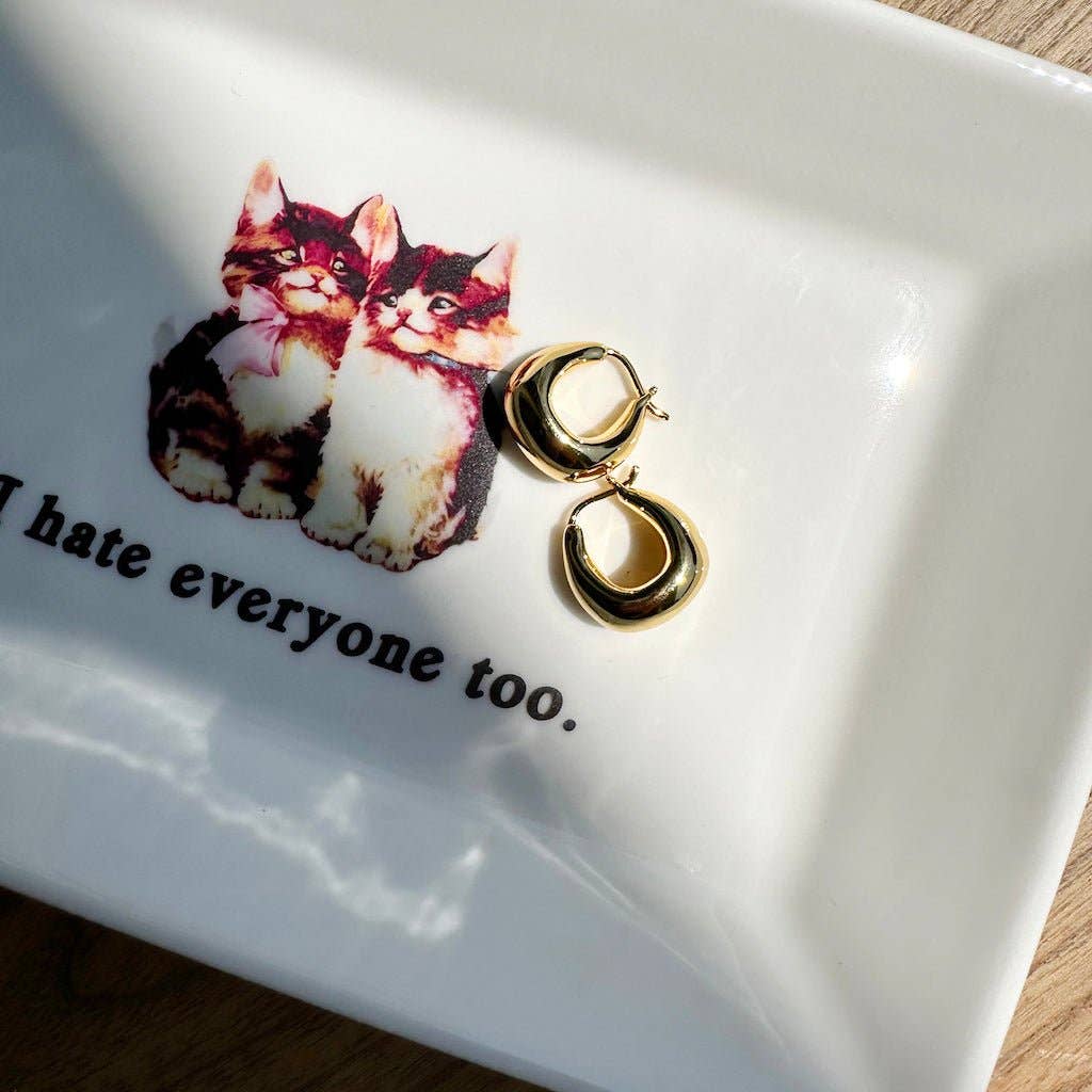 A pair of Dumpling Hoops in Gold on a jewelry tray decorated with a pair of kittens and the words "I hate everyone too."