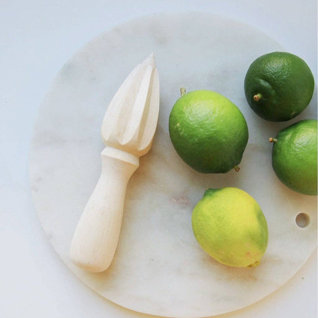 A wooden reamer next to four limes.