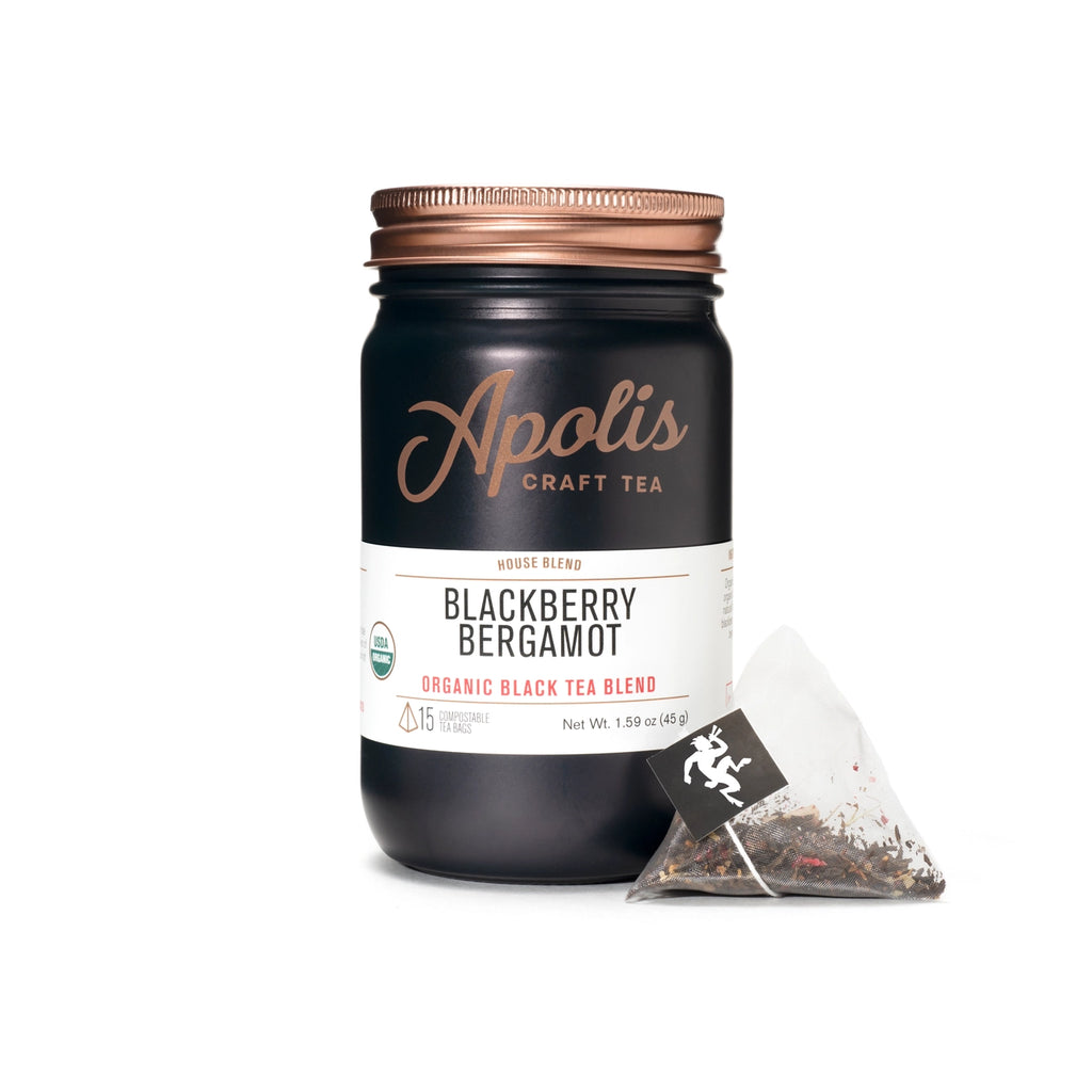 A navy mason jar of Blackberry Bergamot Tea next to a triangle sachet of tea.