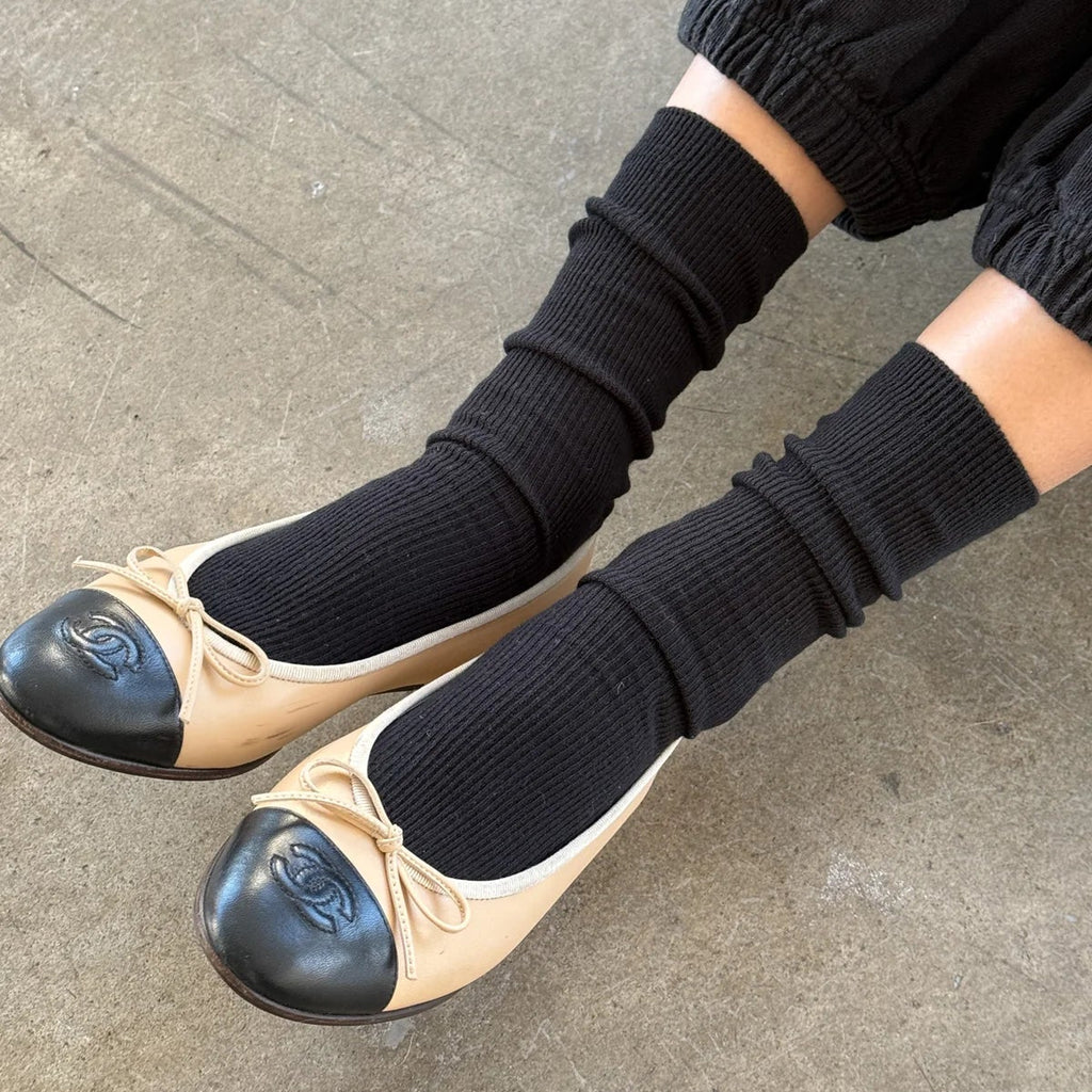 A person wearing the Trouser Socks in Black with a pair of Chanel black and beige flats.