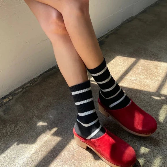 A person wearing the Boyfriend Socks with red clogs.