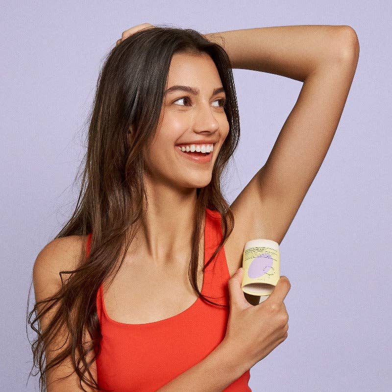 A girl applying the Lavender + Jasmine Deodorant under her arm.