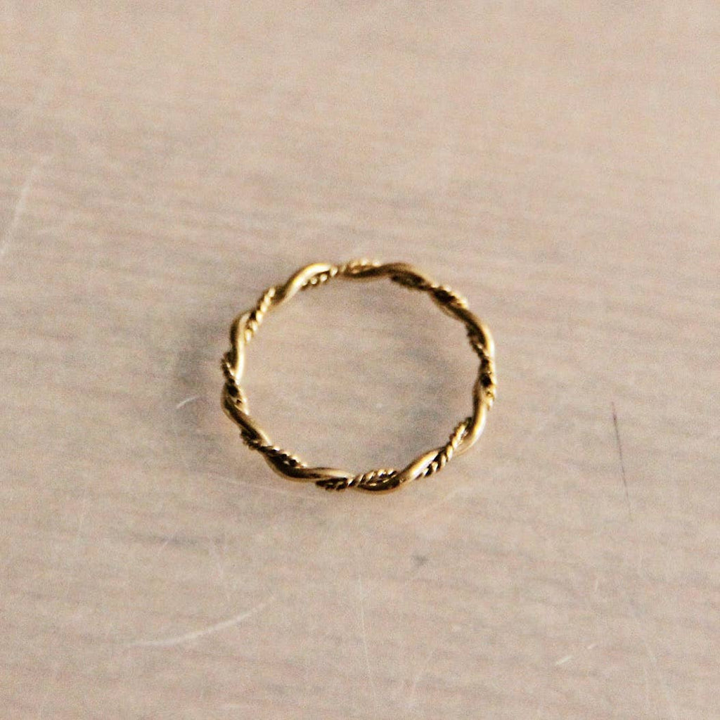 A gold stainless sting ring with a twisted thread of metal wraping around a smooth thread of metal.