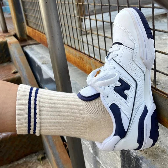 A foot wearing the Cashew Boyfriend Socks with a white and navy blue gym shoe.