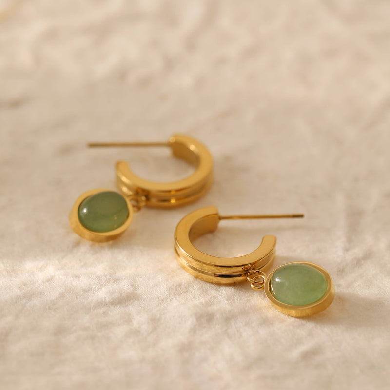 Two gold plated stainless steel huggie hoops with a green aventurine stone encased in gold hanging from the bottom.