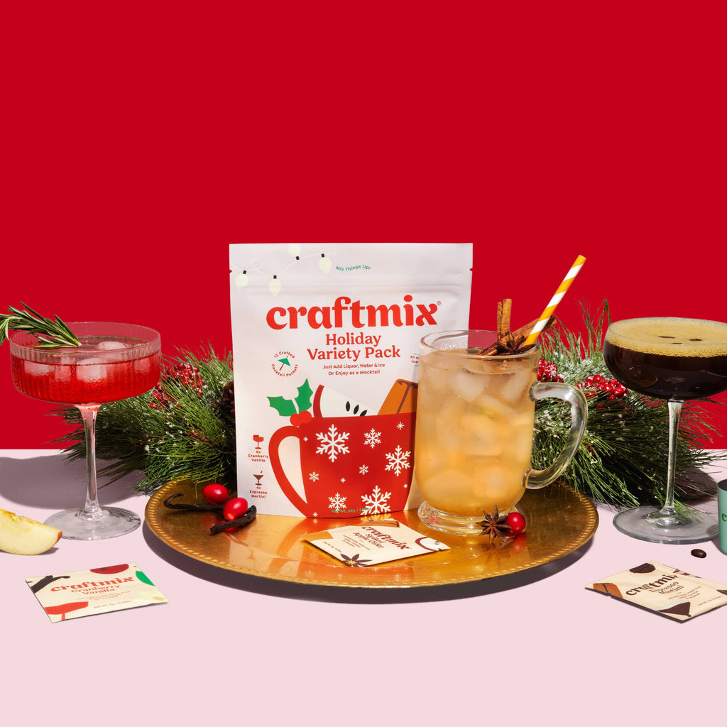 A Holiday Variety Pack surrounded by a Cranberry Vanilla cocktail, an espresso martini, a spiked apple cider, and holiday evergreens and holly.