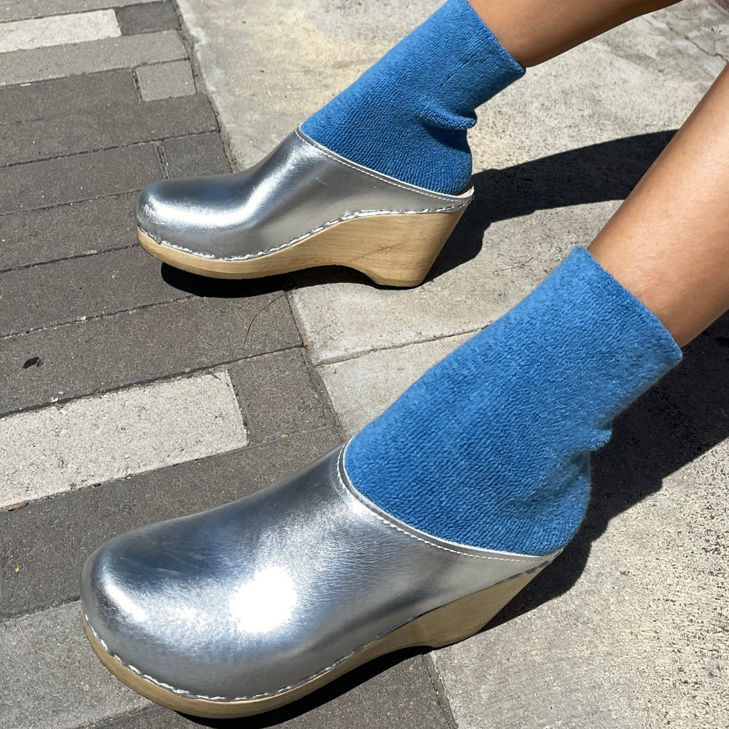 A person wearing the Cloud Socks in Cerulian with silver clogs.