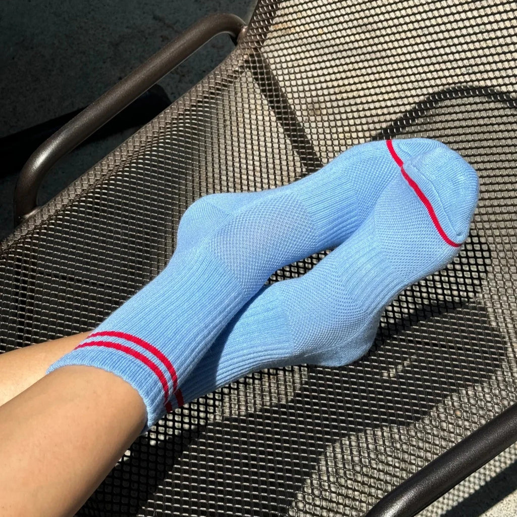 A pair of crossed feet wearing the Ciel Blue Boyfriend Socks while lounging on a chair.