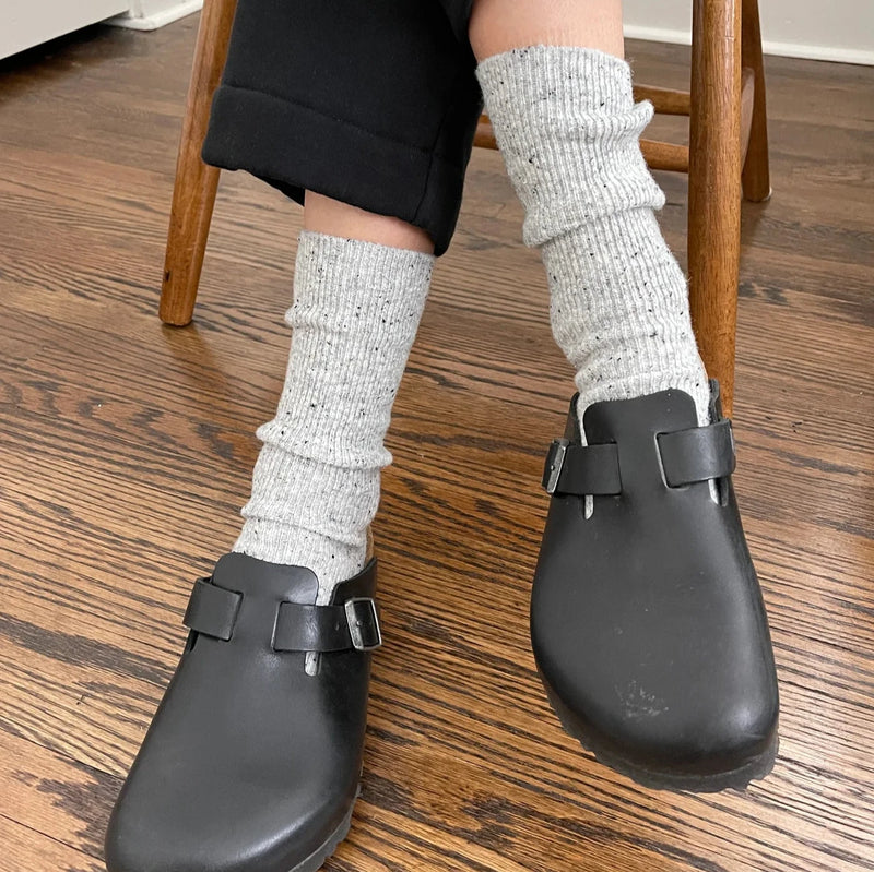 A person wearing the Snow Socks in Cookies & Cream with black slip-on shoes.