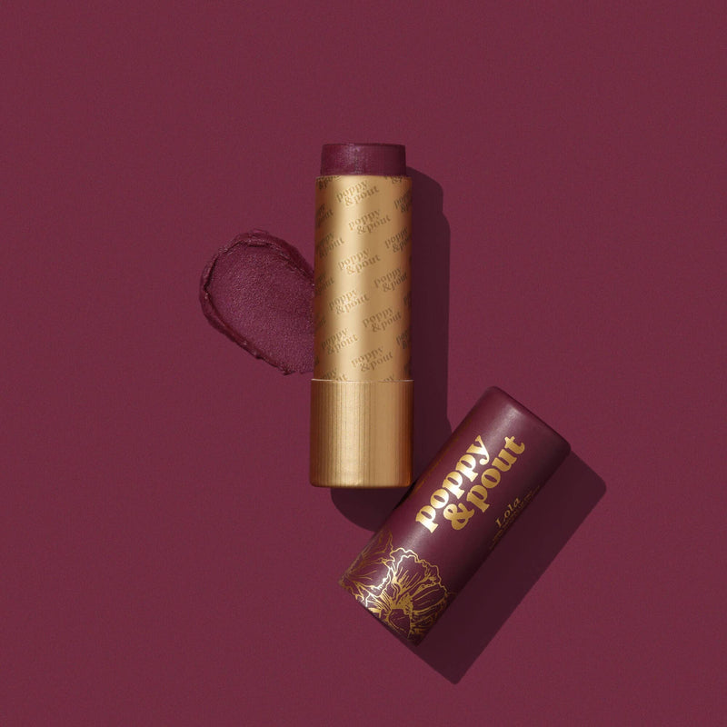 A deep plum colored Lola Lip Tint next to its cap and a swatch against a similar colored background.