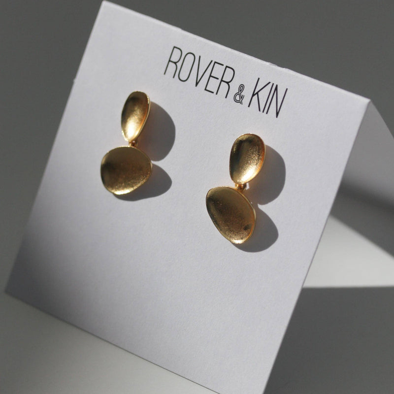 The Luxe Gold Baubles Earrings attached to their folded white paper packaging.