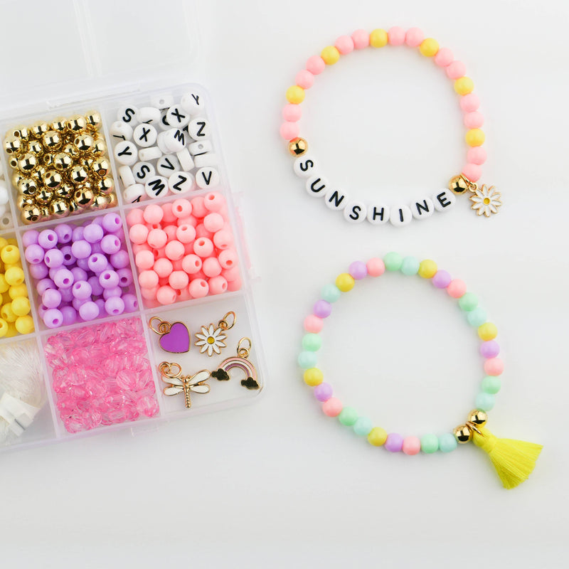 Two pastel beaded bracelets next to a storage box of colorful beads and charms. One bracelet says "Sunshine"  with a daisy charm.