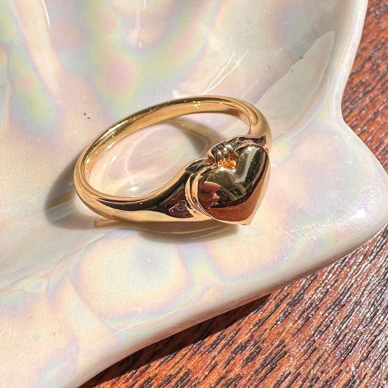 A Heart Locket Ring resting on an iridescent jewelry dish.