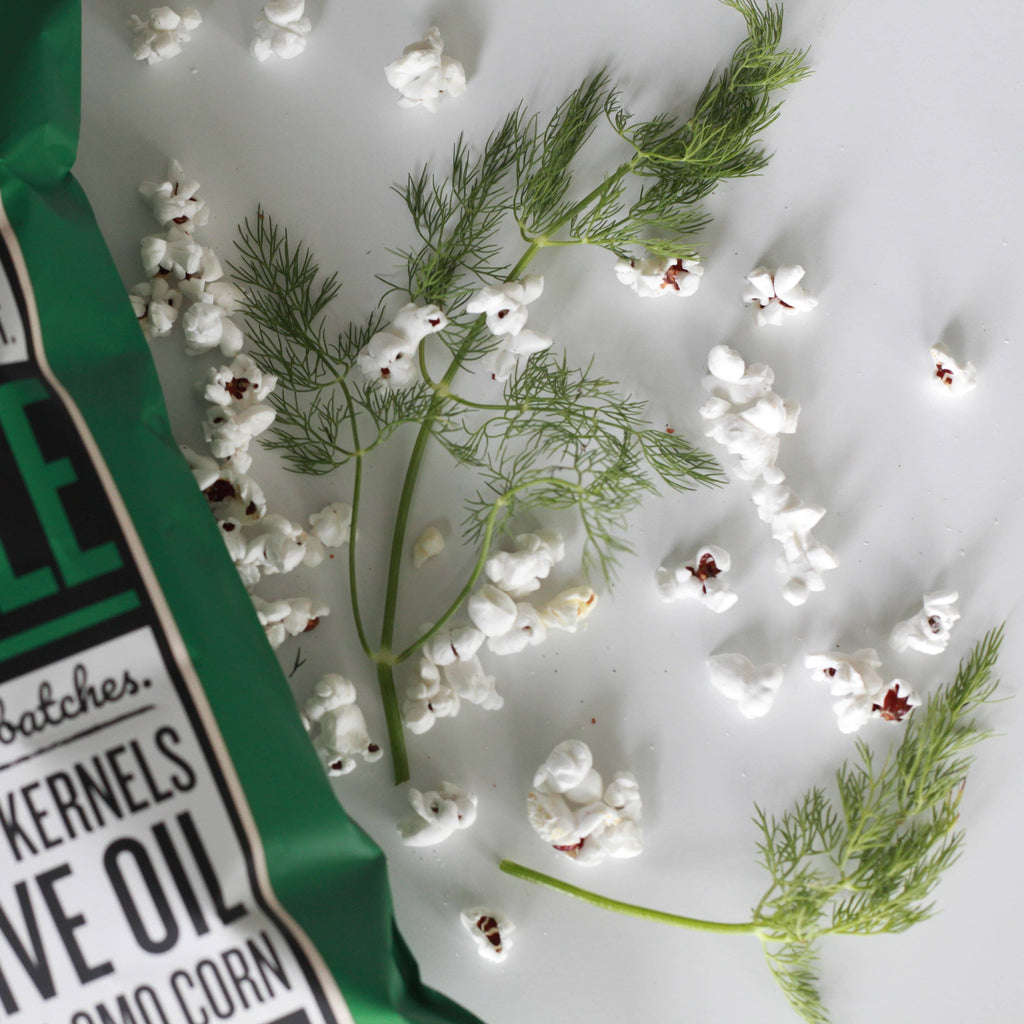 Sprigs of dill surrounded by pieces of dill pickle popcorn.