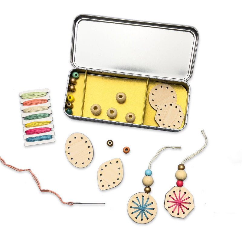 A tin kit with wooden snowflakes, beads, and embroidery thread.