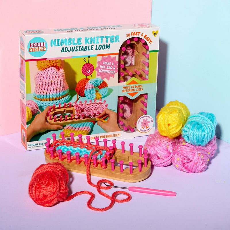 A knitting loom with four balls of yarn and tools.