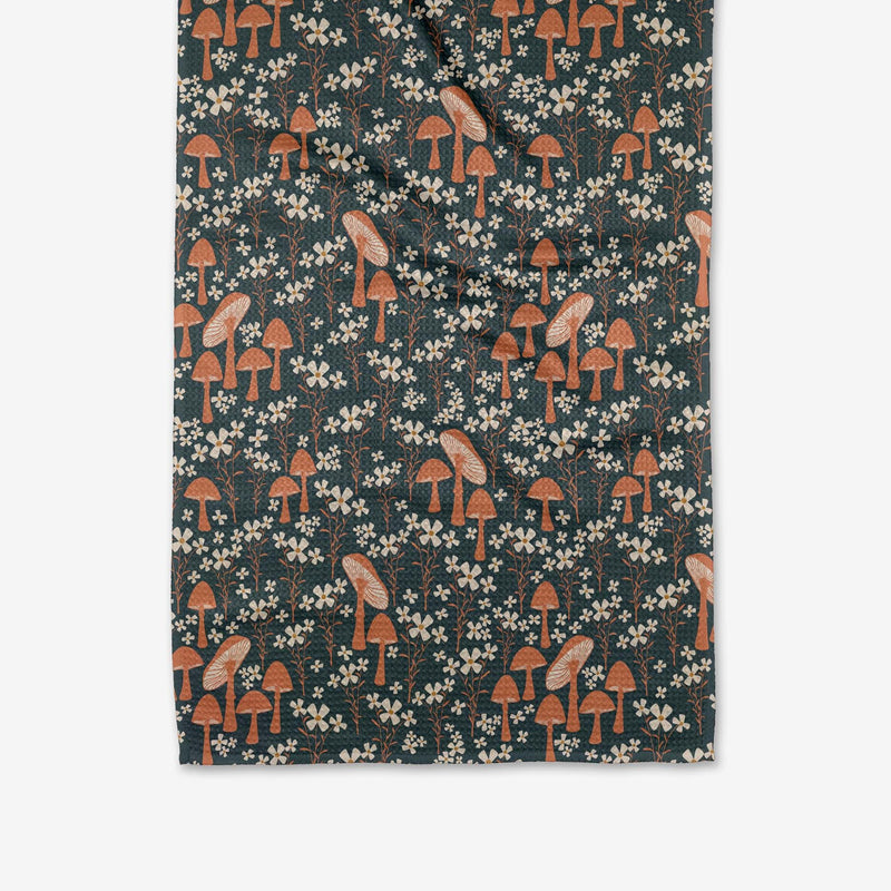 A spruce green Tea Towel with orange and pink mushrooms and white flowers printed across it.