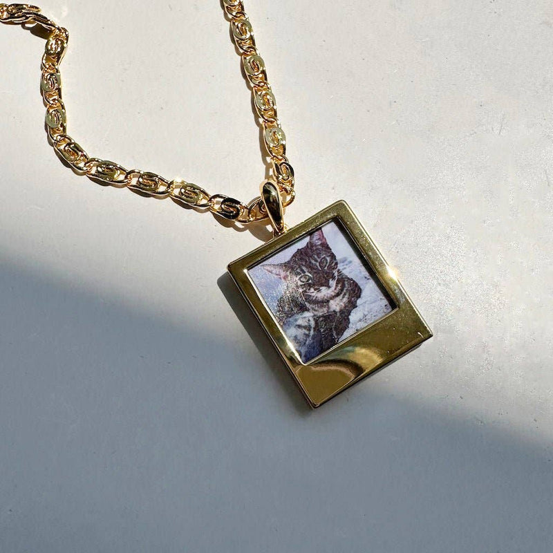 A close-up of the Polaroid Photo Charm on a chain necklace.