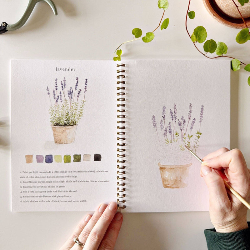 A Garden Watercolor Workbook layout with a pot of lavender on the left and a hand watercolor painting it on the right.