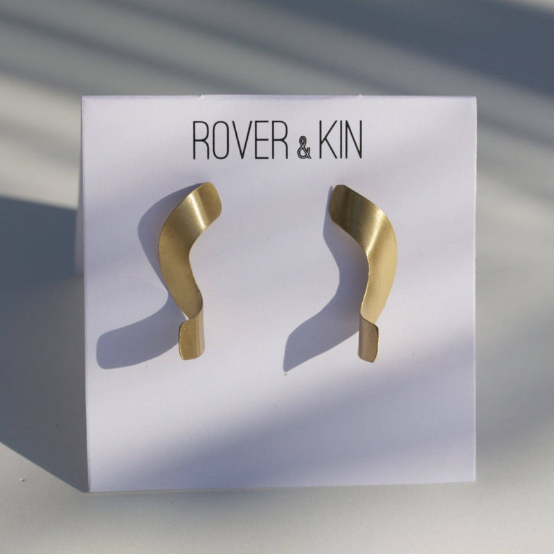 A pair of Golden Noodle Earrings poked through its white paper packaging.