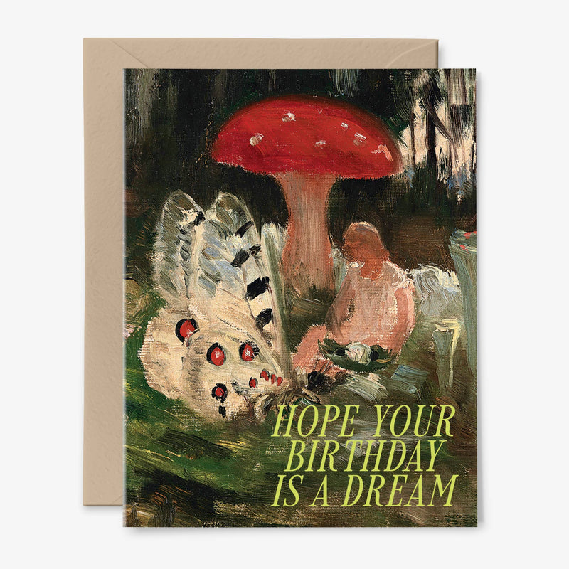 A card illustrated with a fairy sitting under a toadstool nest to a white butterfly and the words "Hope Your Birthday is a Dream" in lime green. There is a kraft envelope behind.