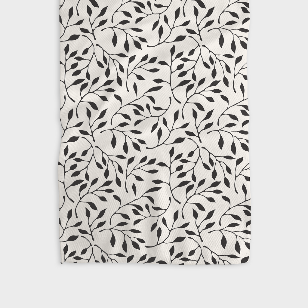 A white tea towel patterned with black branches of leaves.